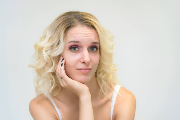 Portrait of a beautiful blonde girl while working as a professional beautician make-up artist. She sits right in front of the camera and looks happy. - Foto, imagen