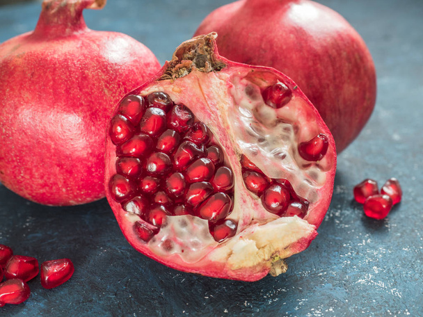 Fresh ripe red pomegranate fruit on a dark blue rustic background. Healthy food, closeup, flat lay, top view - Photo, image