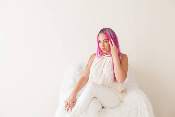 όμορφη γυναίκα με ροζ μαλλιά που κάθεται σε μια πολυθρόνα λευκό - Φωτογραφία, εικόνα