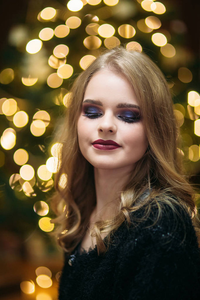 Menina sorridente com bela maquiagem na frente da árvore de Natal
 - Foto, Imagem