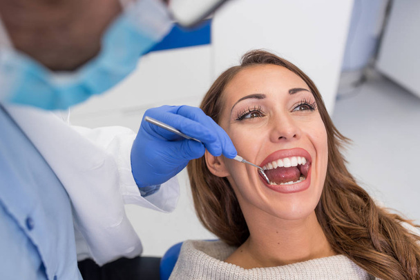 Genç kendine güvenen erkek dişçi klinikte kadın hastaya tıbbi tedavi. Diş Kliniği kavramı - Fotoğraf, Görsel