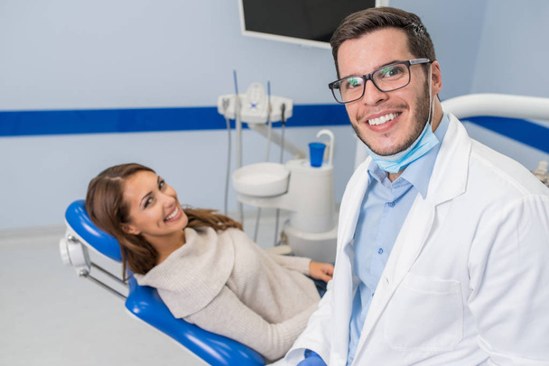Lachende tandarts en Patient in tandheelkundige kliniek  - Foto, afbeelding