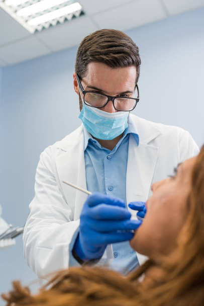 Close-up of male dentist in clinic wearing eye glasses and protect mask - Foto, Bild