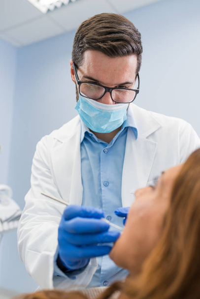 Close-up van mannelijke tandarts in kliniek oog dragen bril en masker te beschermen - Foto, afbeelding