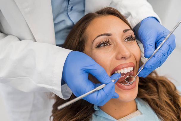 Hoge hoekmening van tandarts examencommissie vrouw met tandheelkundige apparatuur  - Foto, afbeelding