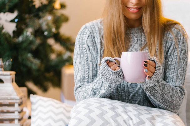Fiatal nő iszik kakaót otthon meleg szürke pulóver - Fotó, kép
