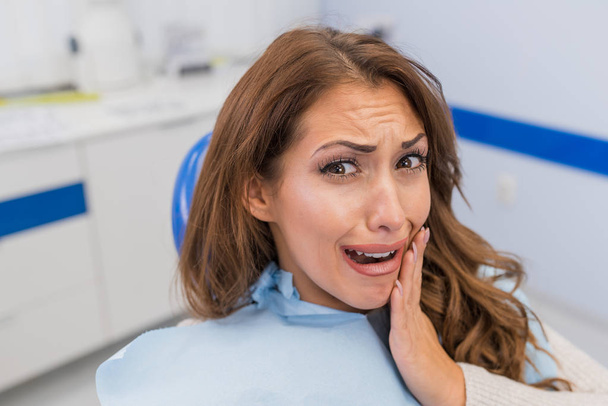 Young woman with tooth pain sitting in a dentist's chair. - Foto, Imagen