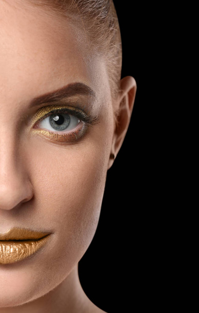 Beautiful woman with golden make up against dark background - 写真・画像