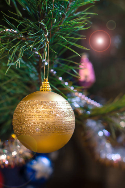 Spruce branch with ball, toys and festive lights with sparkles on the background. Christmas and New Year concept. - Photo, Image