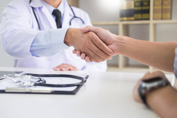 doctor at the clinic giving an handshake to his patient for encouragement and empathy, healthcare and assistance concept - Foto, Imagem