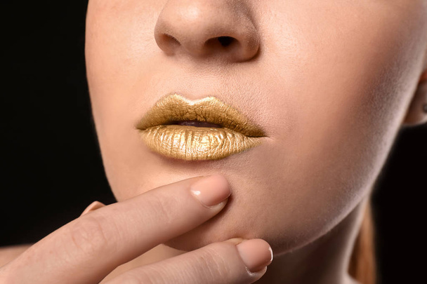 Beautiful woman with golden lips on dark background, closeup - Photo, Image