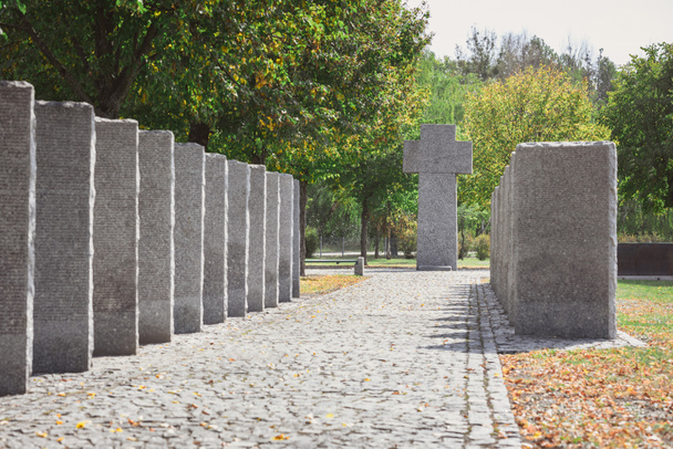 selective focus of identical headstones and stone cross at cemetery  - 写真・画像