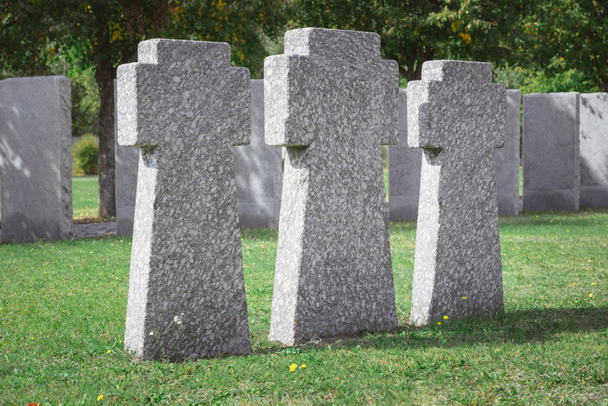 вибірковий фокус меморіальних кам'яних хрестів, розміщених поспіль на кладовищі
 - Фото, зображення