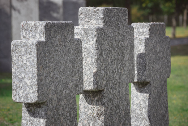 селективный фокус мемориальных каменных крестов, расположенных в ряд на кладбище
 - Фото, изображение