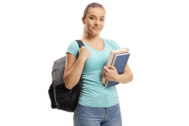Teenage schoolgirl with a backpack holding books isolated on white background - Fotó, kép