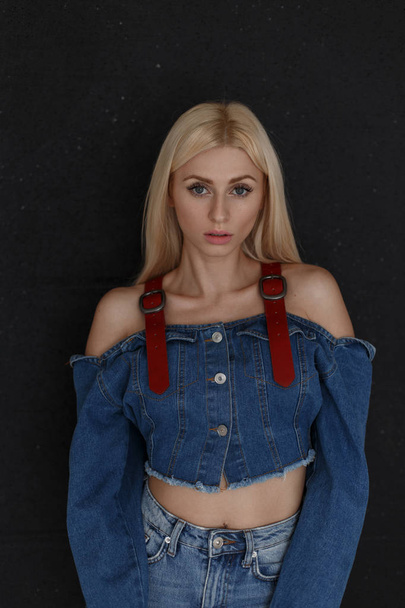 Fashionable beautiful young woman with freckles in vintage jeans clothes with stylish blue jeans on black background - Zdjęcie, obraz