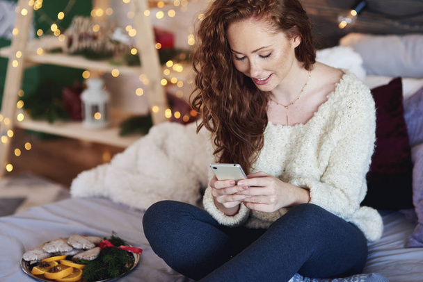 Ragazza con cellulare trascorrere il tempo di Natale a letto
  - Foto, immagini