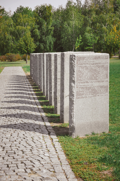 oude memorial grafstenen met belettering geplaatst in rij- en bomen op begraafplaats - Foto, afbeelding