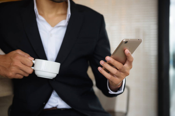 Homme d'affaires barbe arabe jouer smartphone et transporter tasse de café dans le café. Business man chat, surfer sur les médias sociaux, et vérifier le plan de projet à partir de données mobiles en utilisant la technologie 4g
. - Photo, image