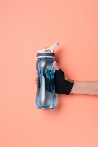 Cropped view of female hand with sport bottle on beige background - Fotó, kép
