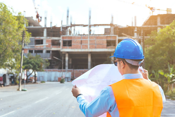 Asian man civil engineer wearing blue safety helmet checking working progress at construction site. - Fotografie, Obrázek
