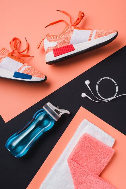Flat lay with sneakers, sport bottle, towel and headphones on black background - 写真・画像