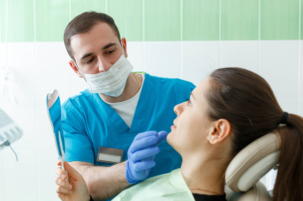 Olgun erkek diş hekimi diş check-up klinik diş hekimliği işgal tedavi tıbbi sanayi sağlık sigorta sahip insanlar bir ayna dişçi ile ziyaret kadın hasta ile çalışma - Fotoğraf, Görsel