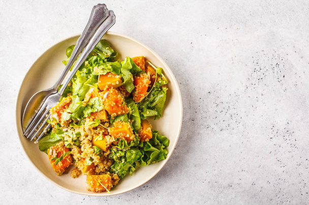 Warm quinoa and pumpkin salad in a white plate. Healthy vegan food concept, diet food. - Fotoğraf, Görsel