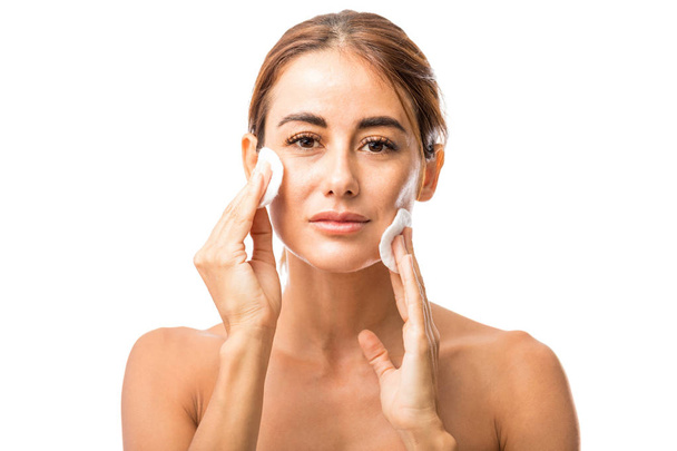 Confiant milieu adulte femme nettoyage ses joues après faciale en studio
 - Photo, image