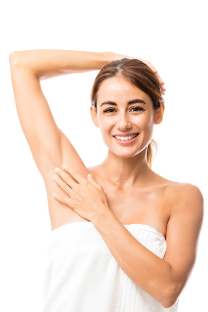 Χαμογελαστός και ελκυστική γυναίκα που αγγίζει το μαλακό μασχάλη μετά το ξύρισμα ενάντια σε λευκό φόντο - Φωτογραφία, εικόνα