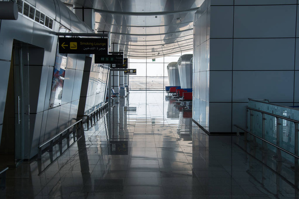 Couloir vide dans la salle des départs avec plaques signalétiques Salon fumeurs, numéros de toilettes et de barrières à l'aérogare internationale
 - Photo, image