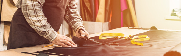 vista parcial del hombre bolso artesano corte de cuero por tijeras en el taller
 - Foto, Imagen