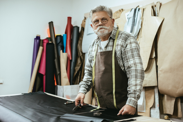 middle aged craftsman in apron and eyeglasses at workshop - Photo, Image