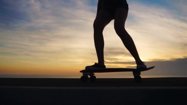 Silhouette close-up di skateboard contro il cielo al tramonto al rallentatore. Piedi con primo piano skateboard
. - Filmati, video