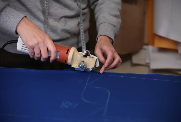Lavoratore tagliare il panno disegnando utilizzando lo strumento. Solo mani
 - Foto, immagini