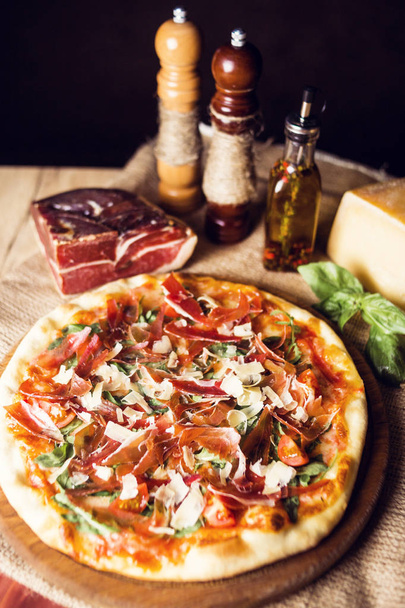 hot fresh pizza wit cheese,ham and basil on wooden plate - Valokuva, kuva
