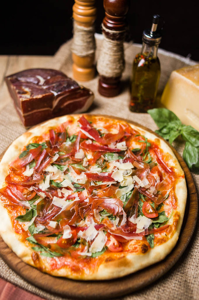 hot fresh pizza wit cheese,ham and basil on wooden plate - 写真・画像
