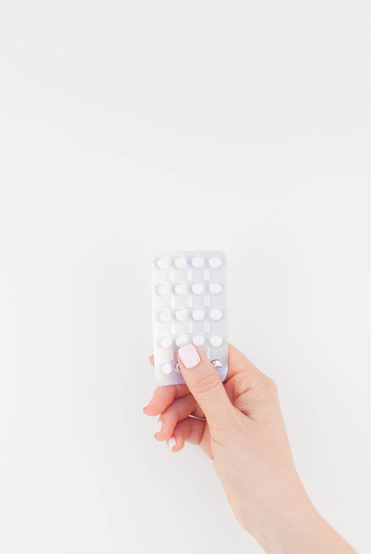 Woman hand with pastel manicure polish holding pills in blister isolated on white background with copy space. Template for feminine beauty blog social media. Female healthcare concept - Fotografie, Obrázek
