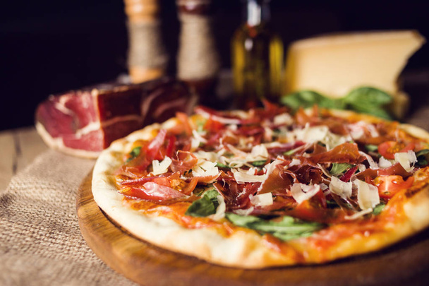 hot fresh pizza wit cheese,ham and basil on wooden plate - Фото, зображення