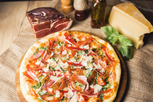 hot fresh pizza wit cheese,ham and basil on wooden plate - Photo, Image