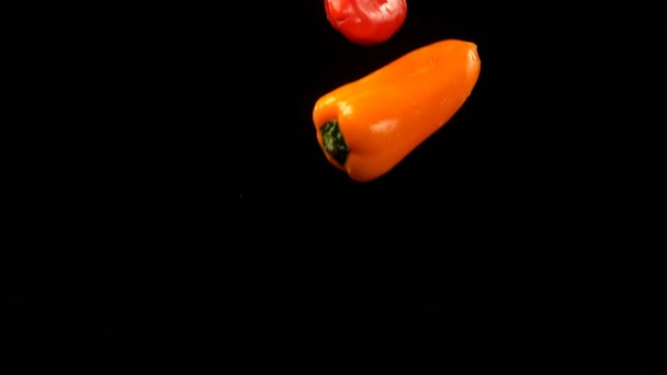 Close-up of bell peppers falling on water against black background 4k - Πλάνα, βίντεο