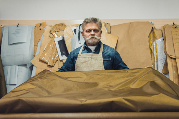fiducioso artigiano borsa maschile di mezza età mettendo tessuto sul tavolo di lavoro in studio
 - Foto, immagini