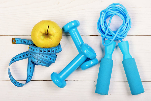 Apple in green color near barbells, centimeter and jump rope - Foto, Imagen