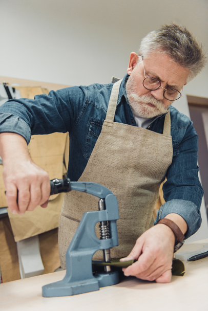 focused male handbag craftsman working with tool at studio - Photo, Image