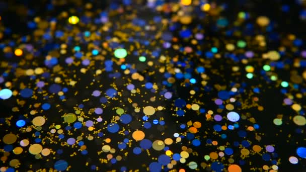 Desfocado cintilante multicolorido glitter confetti, fundo preto. Férias abstrato festivo bokeh pontos de luz
. - Filmagem, Vídeo