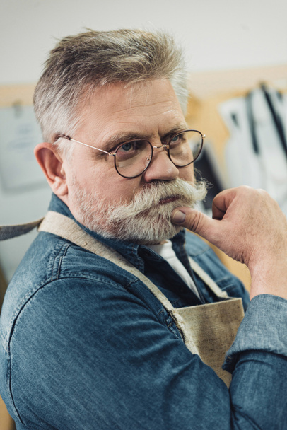 pensativo de mediana edad artesano masculino en delantal posando en el taller
 - Foto, Imagen