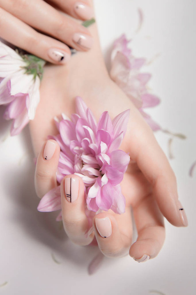 Fashion art skin care and Nude manicure. Pink flowers in hands - Fotoğraf, Görsel