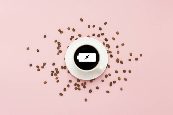 White cup with black coffee, grains of coffee, on a pink background. Sign a charged battery. Concept charge for the day. Flat lay, top view. - Photo, Image