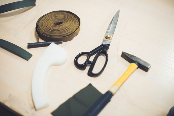 vista de perto da mesa de trabalho com tecido, martelo e tesoura na oficina
  - Foto, Imagem