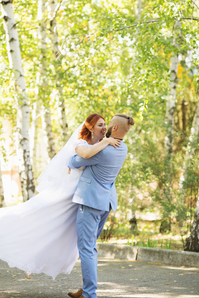 Gewoon liefdevolle hipster echtpaar in trouwjurk en pak in het park. Gelukkige bruid en bruidegom lopen lopen en dansen. Romantische trouwde met jonge gezin. Herfst-bruiloft - Foto, afbeelding